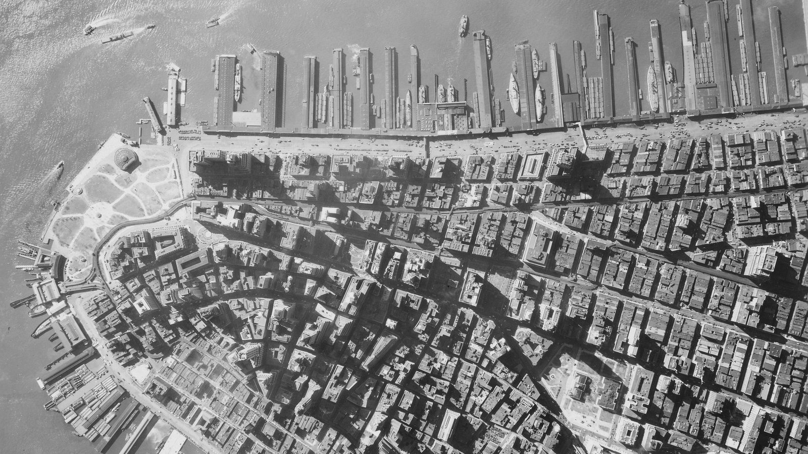 Archival aerial view of Lower Manhattan showing Battery Park, waterfront piers and dense downtown blocks