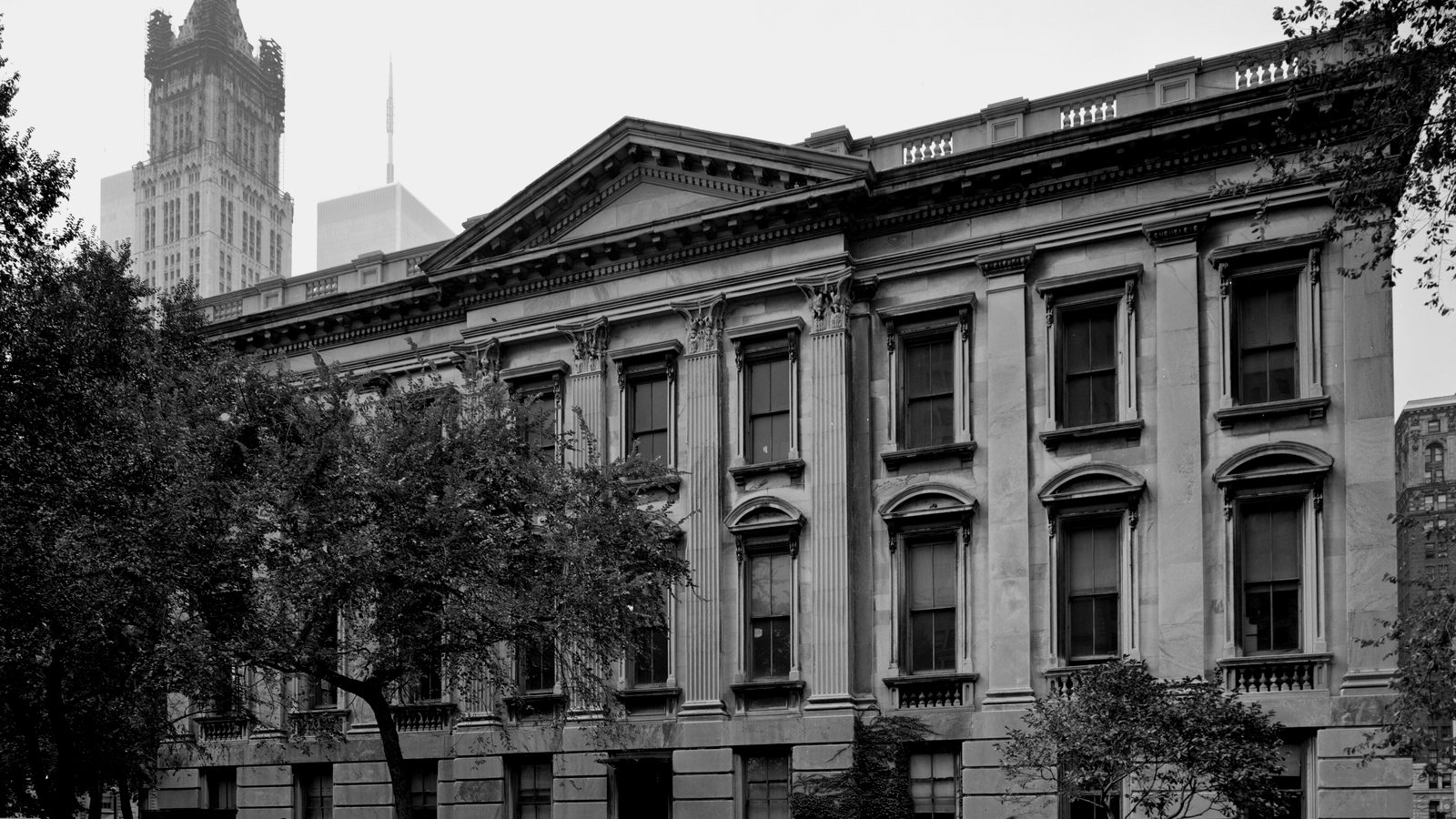 Classical facade of the Tweed Courthouse in Lower Manhattan with pediment and pilasters, Woolworth Building tower behind